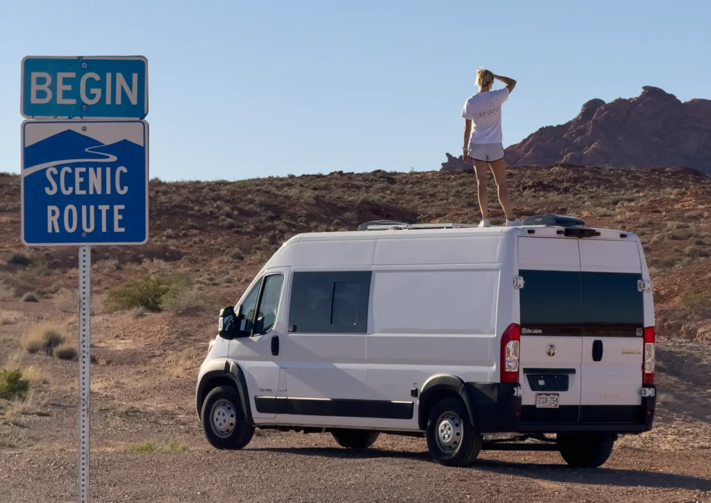 take the scenic route sign with van and girl standing on top