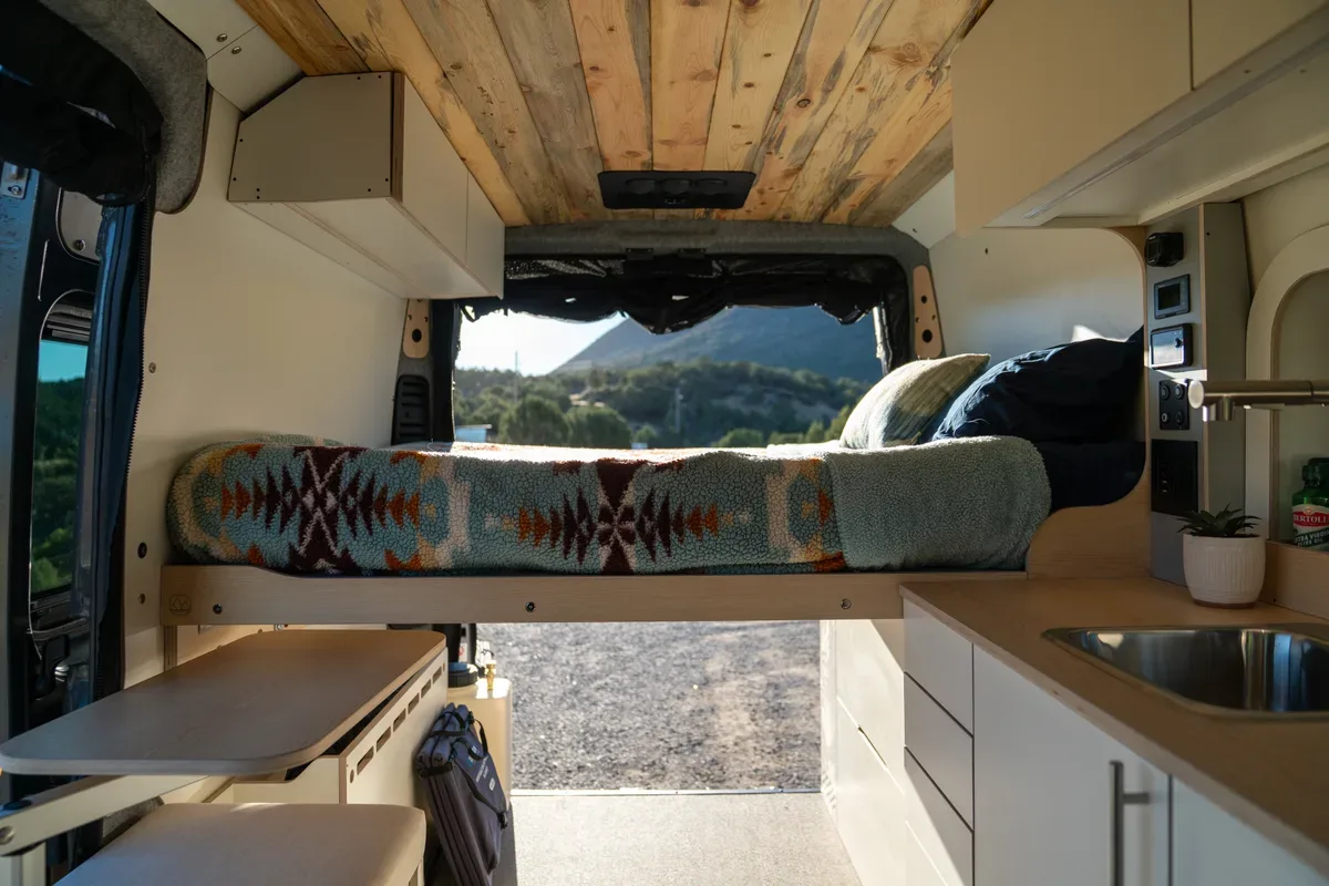 Camper van interior looking back from the cab to the bed and kitchen